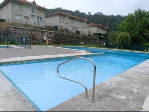 a large swimming pool with a metal hand rail in it at Chalet adosado con piscina en el Valle de Asón LA TUDANCA in Arredondo