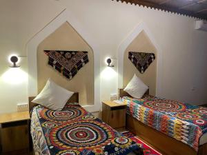 a room with two beds and two pillows on the wall at Anoragul guest house in Shahrisabz