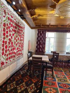 a dining room with tables and chairs and a painting at Anoragul guest house in Shahrisabz +4 photos