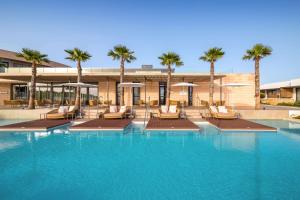 a large swimming pool with chairs and palm trees at Barceló Nura in Sant Lluis