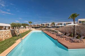 a swimming pool with chairs and a resort at Barceló Nura in Sant Lluis