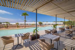 a patio with tables and chairs next to a swimming pool at Barceló Nura in Sant Lluis +59 photos