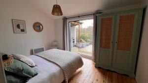 a bedroom with a bed and a sliding glass door at Les Iris - Maison chaleureuse in Montigné-sur-Moine