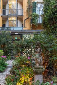 a statue in a garden in front of a building at Hotel Sanpi Milano in Milan