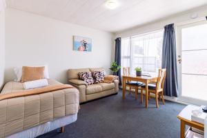 a bedroom with a bed and a table and a couch at Belle Bonne Motel in Christchurch