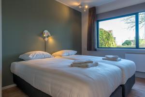 a bedroom with a large bed with two towels on it at Zeebries in De Koog