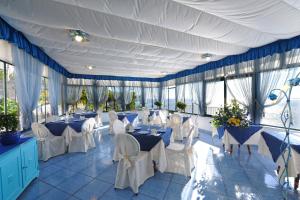 um restaurante com mesas e cadeiras brancas e janelas em Hotel Torre Saracena em Praiano