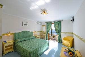 Un dormitorio con una cama verde y una silla amarilla en Hotel Torre Saracena, en Praiano