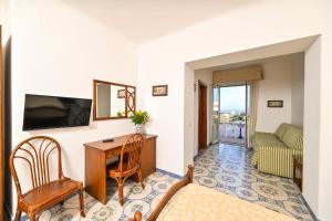 a living room with a desk and a television at Hotel Tramonto d'oro Terme Casthotels in Forio d'Ischia