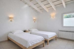 two beds in a room with white walls and a window at Bella Mar in Son Carrio