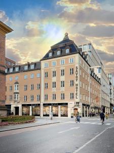 a large building on a city street with people riding bikes at Savoy 1918, a member of Small Luxury Hotels of The World in Oslo