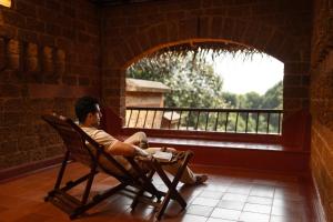 a man sitting in a chair looking out a window at SwaSwara Wellness - A CGH Earth Experience, Gokarna in Gokarna