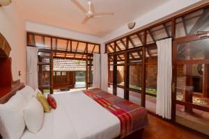a bedroom with a bed and large windows at SwaSwara Wellness - A CGH Earth Experience, Gokarna in Gokarna