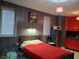 a bedroom with a red bed and a kitchen at Studio Nera in Pomorie