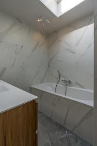 a white bathroom with a tub and a sink at Zeebries in De Koog +9 photos