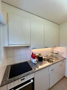 a kitchen with white cabinets and a sink at Cozy Studio in Witikon District in Zurich