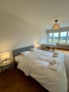 a bedroom with a large white bed and a table at Cozy Studio in Witikon District in Zurich
