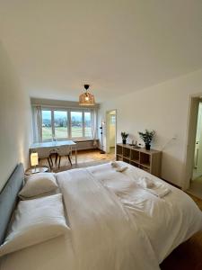 a large white bed in a room with a piano at Cozy Studio in Witikon District in Zurich
