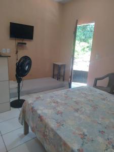 a bedroom with a bed with a fan and a television at kitinete - SALVATERRA GUARAMIRANGA in Guaramiranga