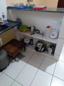 a kitchen with a counter and a shelf with pots and pans at kitinete - SALVATERRA GUARAMIRANGA in Guaramiranga