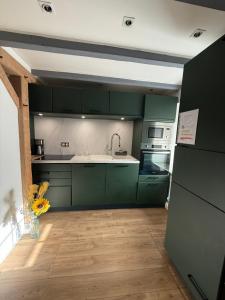 a kitchen with green cabinets and a vase of flowers at Maison in Maisdon-sur-Sèvre