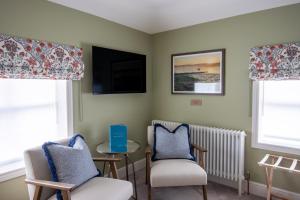 a room with two chairs and a table and a tv at The Bell Hotel, Saxmundham in Saxmundham