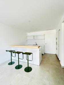 a kitchen with a white counter and two green stools at Rare T2 New, Waterfront in Porticcio