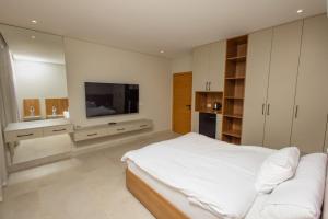 a white bedroom with a large bed and a television at Family Nexus Hotel - Carefree in Hurghada