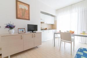 a kitchen with white cabinets and a table with chairs at Residence Selenis Apartments in Caorle