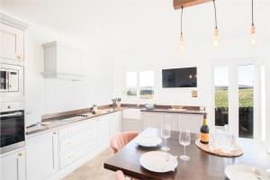 a white kitchen with a wooden table with wine glasses at Northern Hideaways, Sunnyside, Otterburn in Otterburn