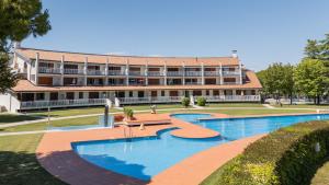 a building with two swimming pools in front of a building at Residence Selenis Apartments in Caorle