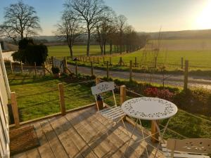 a patio with a table and chairs and a view of a field at The Mad Hatter's Shepherd's Hut in Carlisle