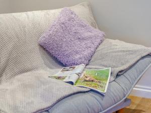 a magazine sitting on a couch with a purple pillow at The Cottage-Uk32854 in Neath