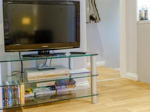 a television on a glass shelf with books and dvds at The Cottage-Uk32854 in Neath
