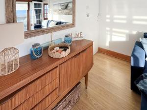 a living room with a wooden dresser with a mirror at Angie's Beachside House in Saint Osyth