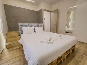 a bedroom with a large white bed with towels on it at Athenian Hideaway - Spa Tub and Walk to Metro in Athens