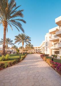 a walkway in front of a resort with palm trees at Hurghada Long Beach Resort in Hurghada