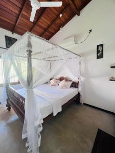a bedroom with a bed with a mosquito net at Sunil VIlla in Talpe