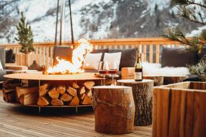 a patio with a fire pit and a table with wine glasses at Lodji Hotel & spa in Saint-Martin-de-Belleville +41 photos
