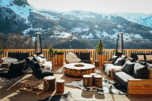 a deck with couches and a table and mountains at Lodji Hotel & spa in Saint-Martin-de-Belleville