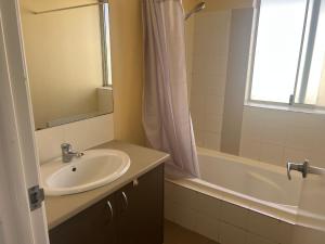 a bathroom with a sink and a mirror and a tub at Homy Kwinana in Wellard