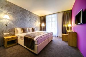 a bedroom with a bed and a purple wall at Hotel Restaurant Darwin in Prague