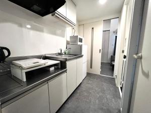a kitchen with white cabinets and a black counter top at イマココホテル in Yogi