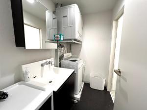 a white bathroom with a sink and a refrigerator at イマココホテル in Yogi
