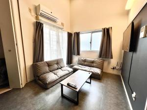 a living room with a couch and a table at イマココホテル in Yogi