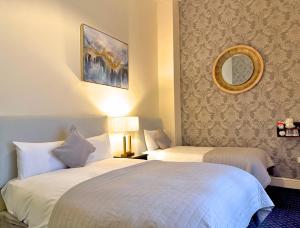 a hotel room with two beds and a mirror at Fitzwilliam Townhouse in Dublin