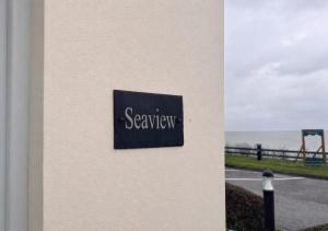 a sign on the side of a building next to the ocean at Seaview Cottage in Llanddulas