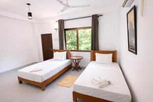 two beds in a room with a table and a window at The Jungle Pearl Hotel in Udawalawe +48 photos