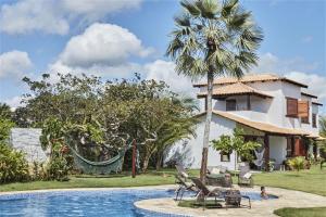 a villa with a palm tree and a swimming pool at Condomínio Villa Conduru - Casa completa in Prea