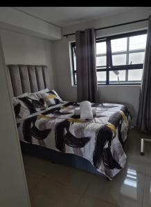 a bedroom with a bed with a comforter and a window at Tettey Haven Millennial in Durban +2 photos
